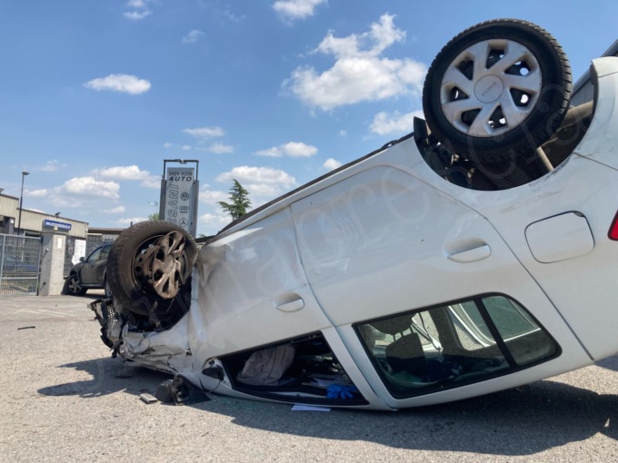 Si schianta contro un’auto parcheggiata e finisce ruote all’aria