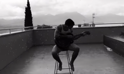 Blanco suona la chitarra sotto la pioggia